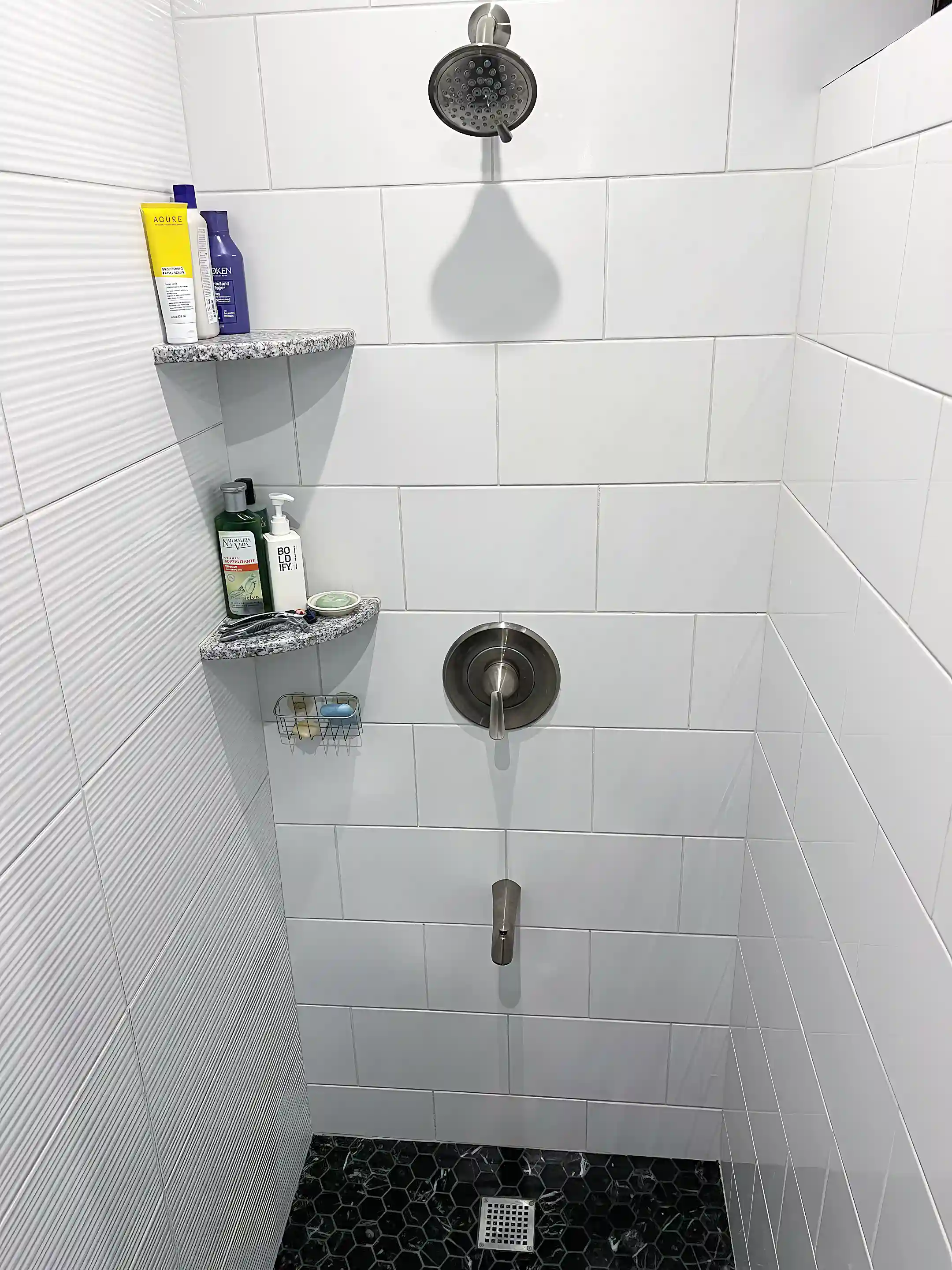 Shower view with white porcelain tile, granite corner soap dishes,...