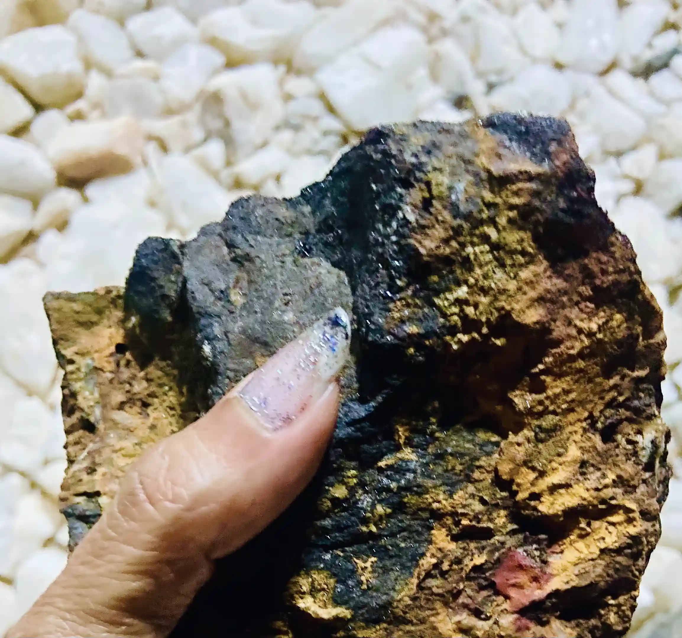 A hand presents a raw, naturally-occurring geological specimen found abundantly...